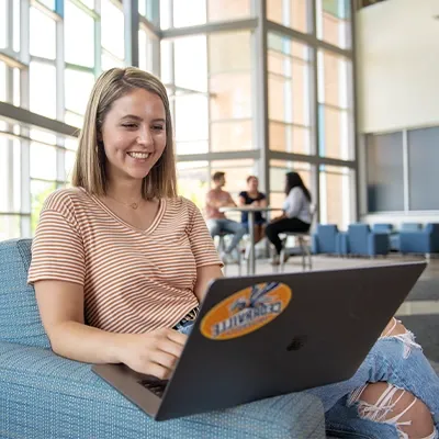 女学生在大楼里用笔记本电脑学习