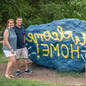 Parents smiling by rock that says 