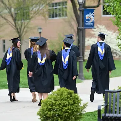 穿着毕业礼服的学生在人行道上聊天